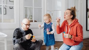 Family enjoying quality time blowing bubbles indoors, capturing joyful moments.